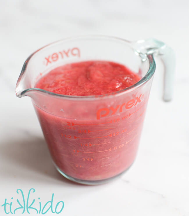 Two cup pyrex measuring cup filled with stewed rhubarb on a marble surface.