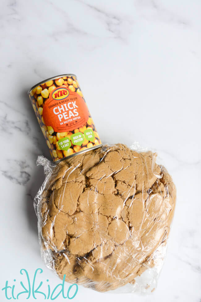 Eggless gingerbread house dough made with canned chickpea liquid  on a white marble surface.