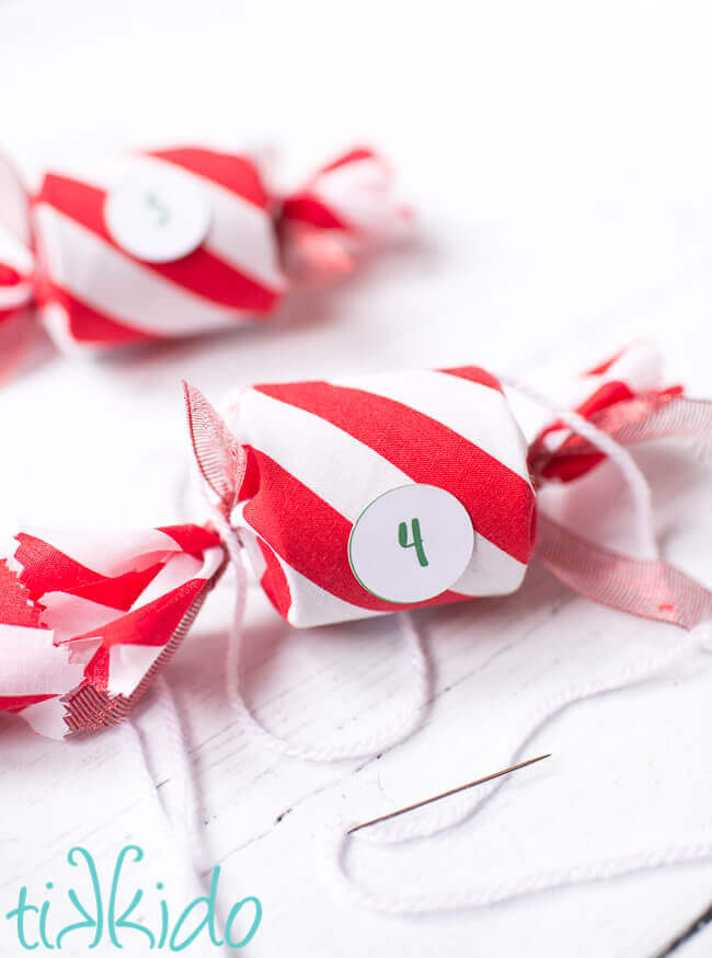 Pieces of a DIY Advent Calendar being strung together with yarn to create an advent calendar garland.