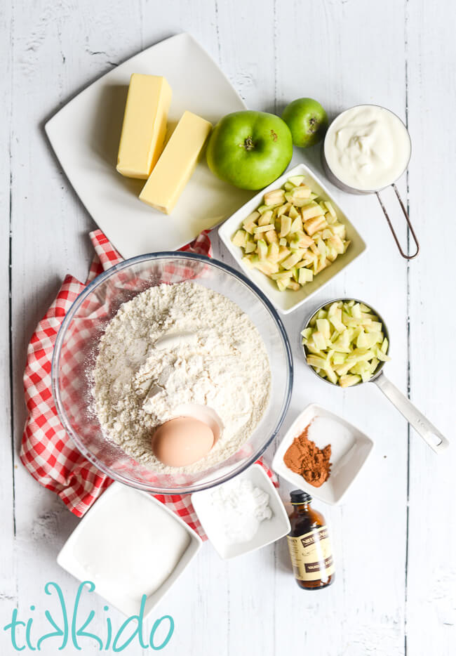 Ingredients for apple scones recipe measured out on a white wooden surface.