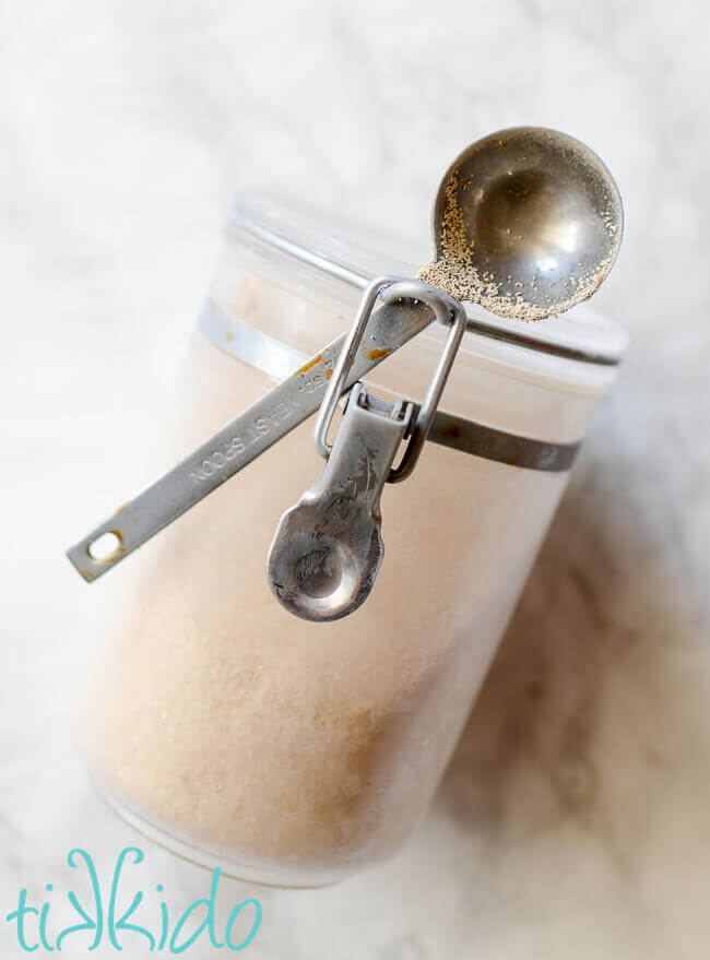 Container of yeast with special yeast spoon on a white marble background