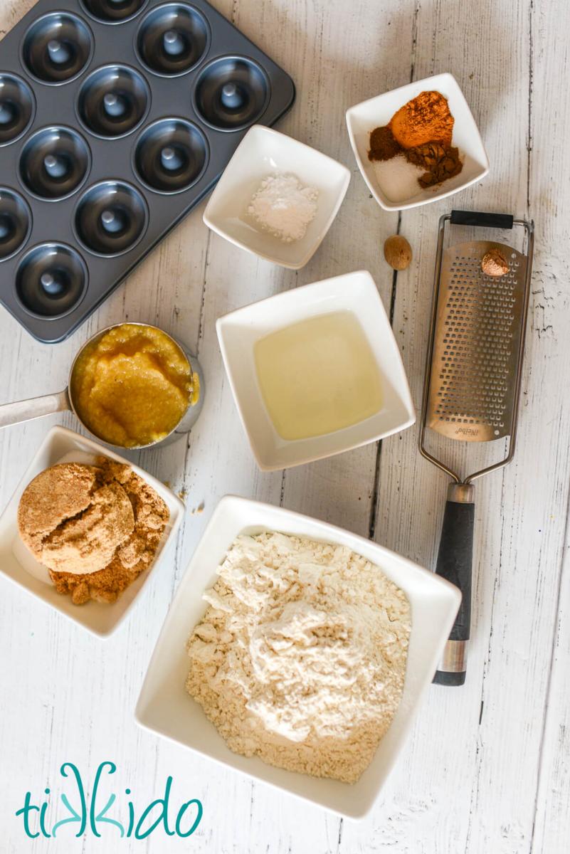 Ingredients for apple cider donuts on a white wooden surface.