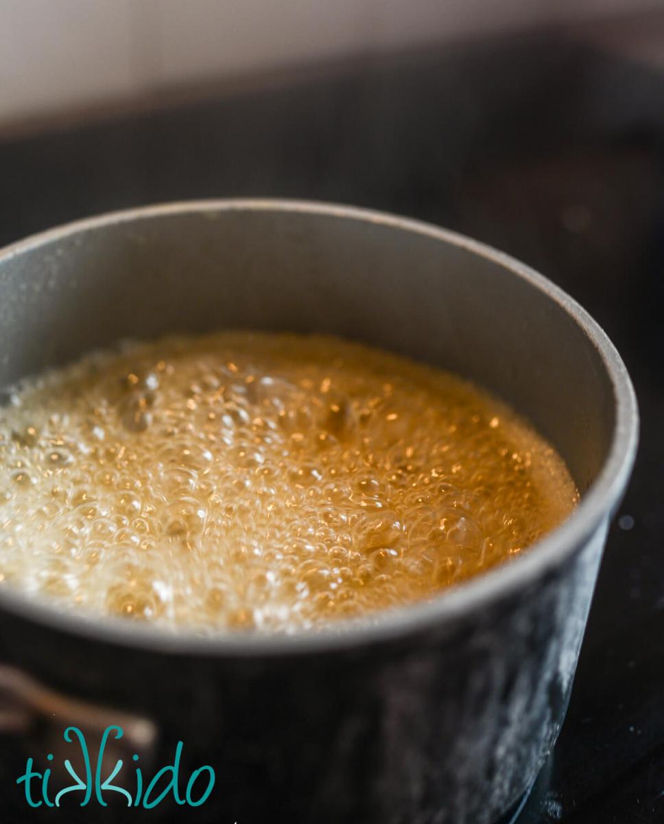 Apple cider reducing in a small saucepan.