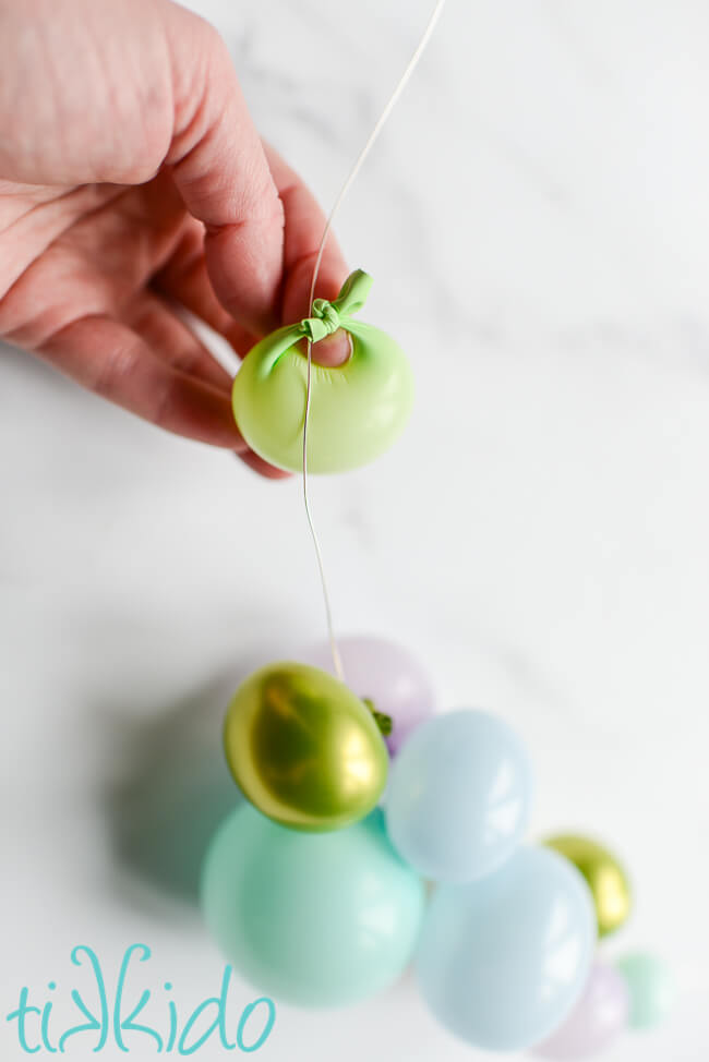 Mini balloons made from 260 twisting balloons being strung on wire to make a Balloon Garland Cake Topper.