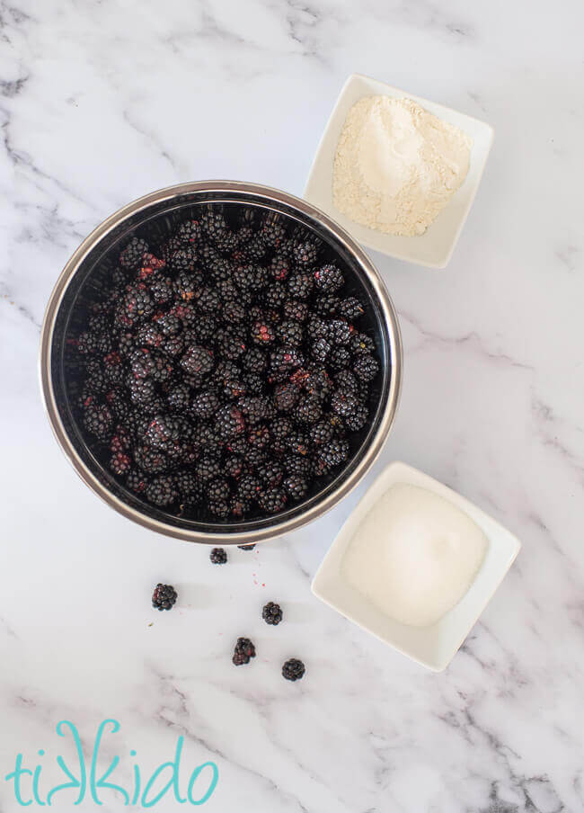 Blackberry crisp filling ingredients on a white marble background.