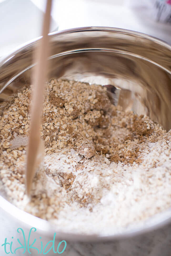 Ingredients for blackberry crisp topping being mixed in a silver bowl.