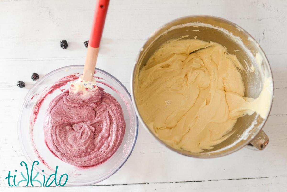 Blackberry Pound Cake Recipe Vanilla and blackberry pound cake batters in two separate bowls on a white wooden surface. A spatula is in the bowl of blackberry pound cake batter.