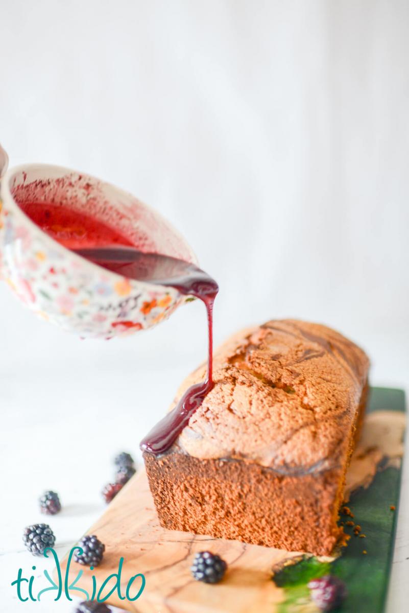 Blackberry Pound Cake Recipe Blackberry glaze being poured over a loaf of blackberry pound cake.