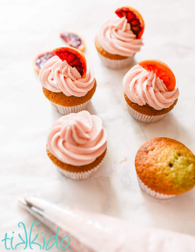 Naturally pink blood orange buttercream icing being piped on blood orange cupcakes.