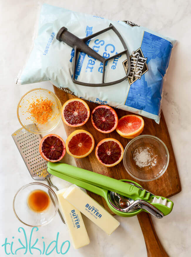 Ingredients for blood orange icing on a white marble background.