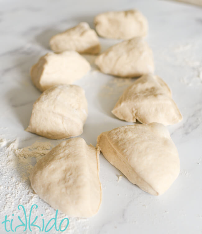 Dough divided into 8 pieces on a lightly floured marble surface to make Auntie Anne's pretzel recipe.