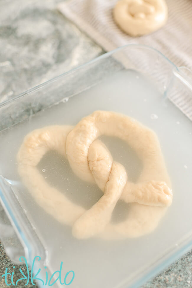 Auntie Anne's copycat pretzel being dipped in a baking soda bath before baking.