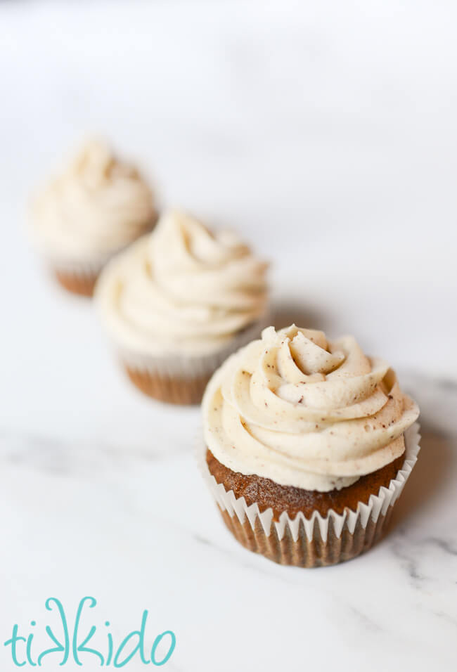 Browned Butter Frosting swirled on three cupcakes sitting in a row.