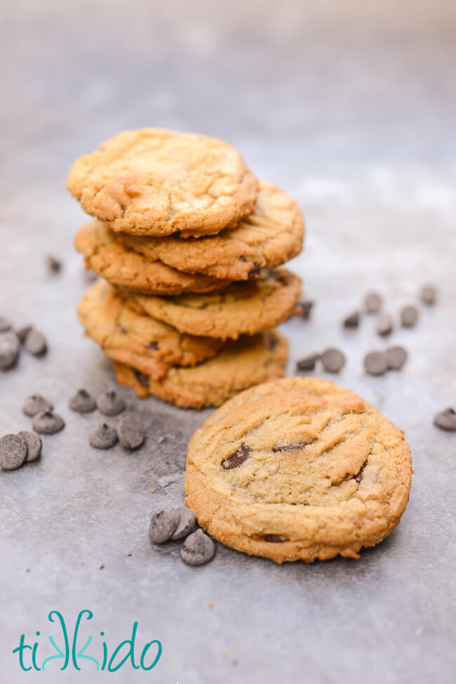 Stack of Browned Butter Chocolate Chip Cookies on a grey surface, surrounded by scattered chocolate chips.