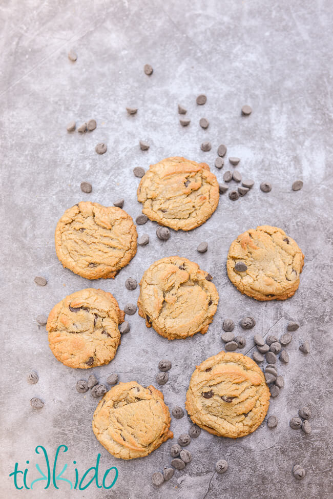 Overhead view of Browned Butter Chocolate Chip Cookies on a grey concrete surface, surrounded by scattered chocolate chips.