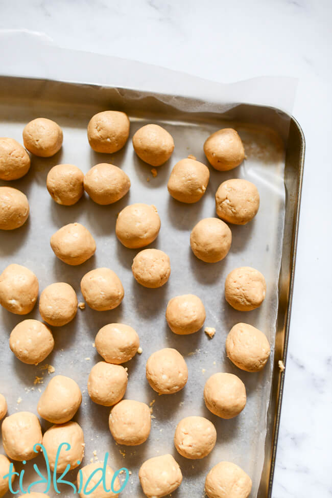 Wax paper lined baking tray full of peanut butter balls ready to be dipped in chocolate to make Buckeye Candies.