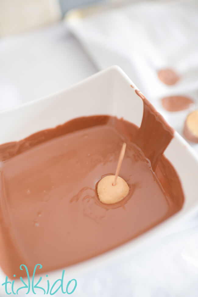 Peanut butter ball being partially dipped in melted chocolate to make Buckeye Candy.