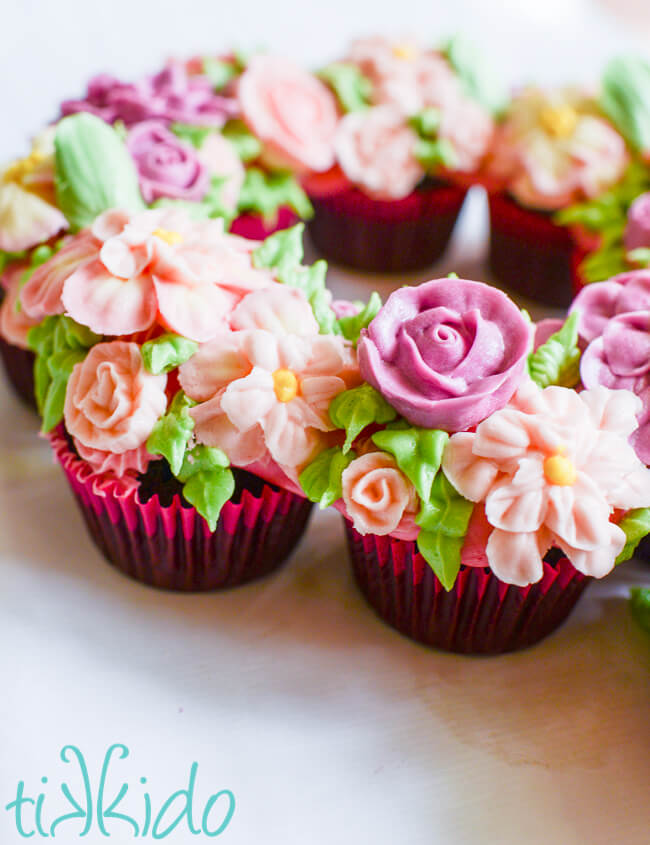 Close-up side view of a cupcake cake decorated with pink and purple icing flowers.