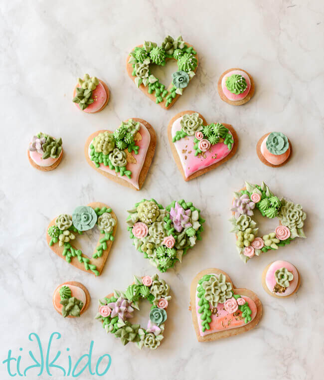 Heart and round shaped sugar cookies, covered in watercolor painted royal icing, with gold leaf and piped succulents.