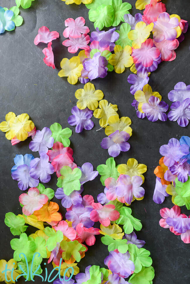 Colorful silk flowers on a black chalkboard background.