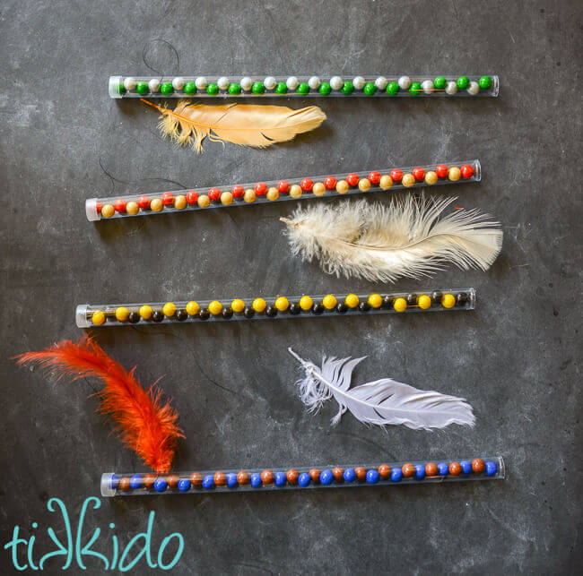 Four clear plastic candy wands filled with Hogwarts house colors chocolate candies, feather attached with black thread to the top of each wand.