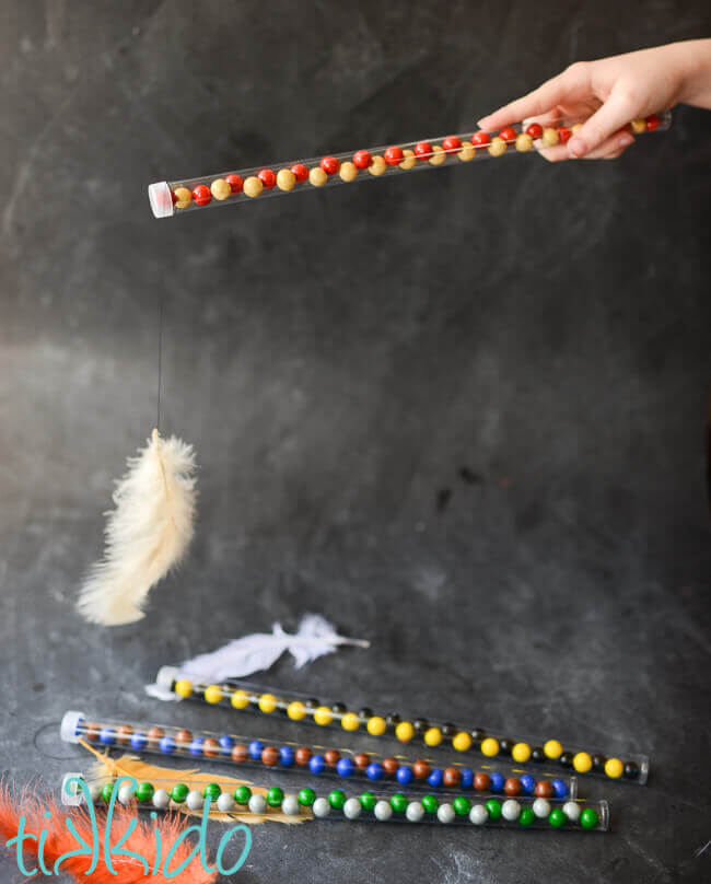 Hand holding candy wand filled with red and gold Gryffindor colors candies, with a feather appearing to levitate in front of the wand.