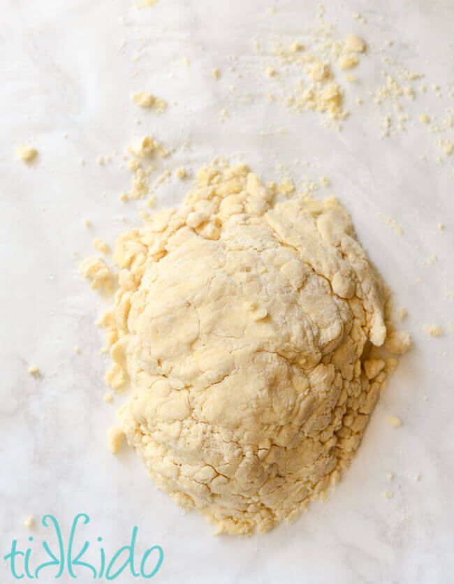 Pile of pie crust dough on a white marble surface.