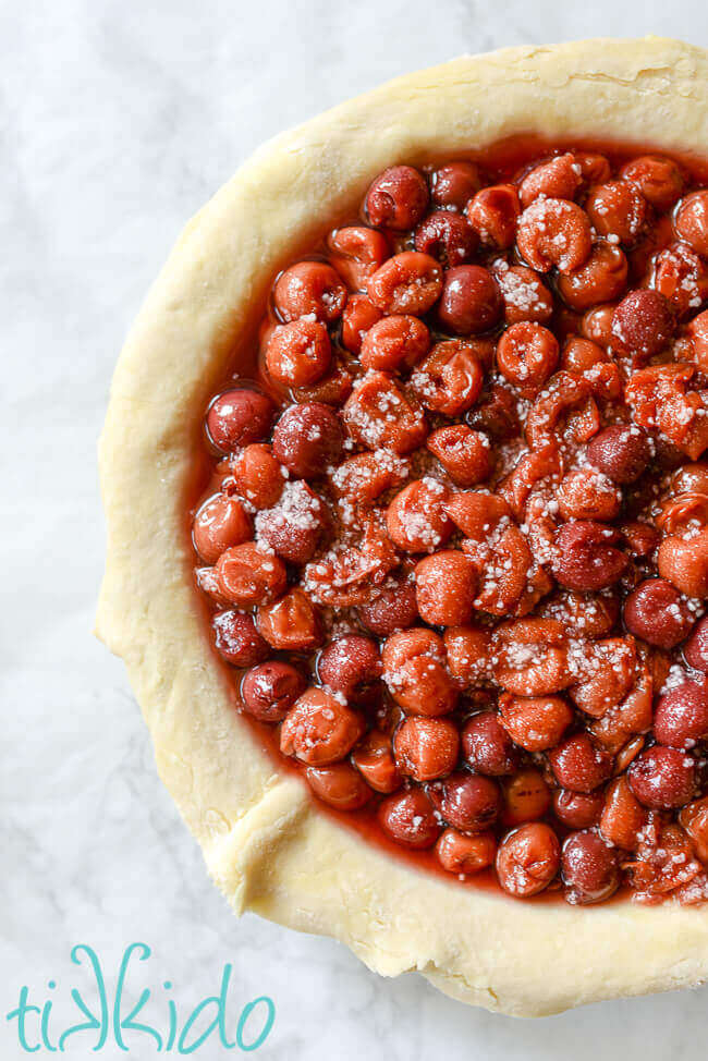 Unbaked pie crust and cherry pie filling in a pie tin.