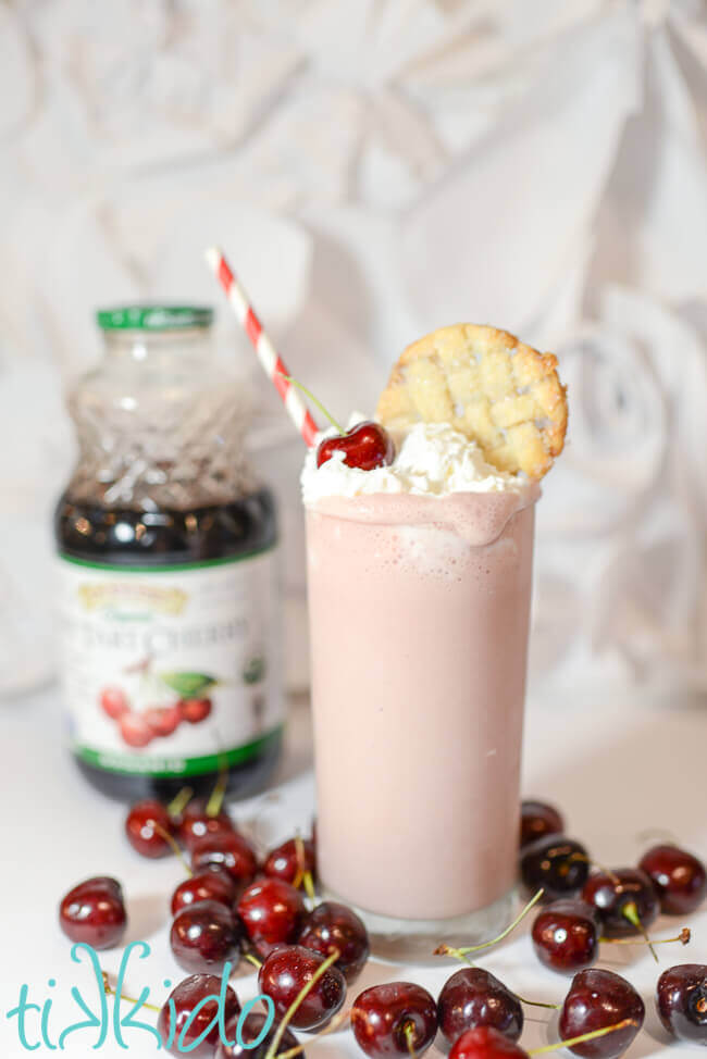 Cherry pie milkshake topped with whipped cream, a fresh cherry, and a circle of lattice pie crust.