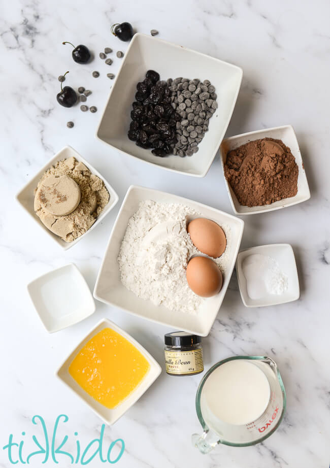 Ingredients for chocolate cherry muffins on a marble surface.