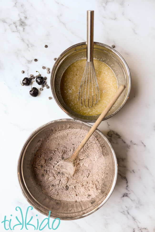 Wet ingredients and dry ingredients for making cherry chocolate muffins in separate bowls.