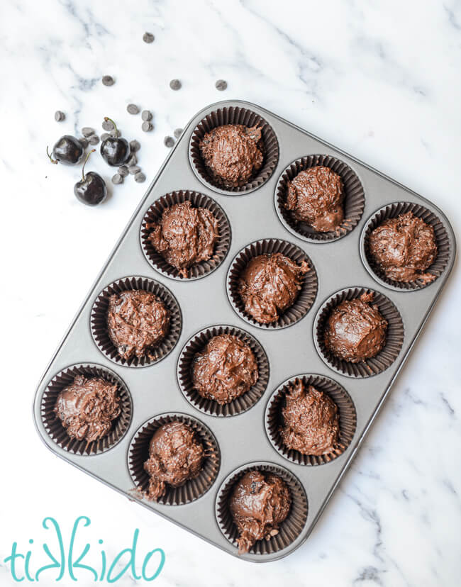 Cherry chocolate muffin batter in a lined muffin tin.