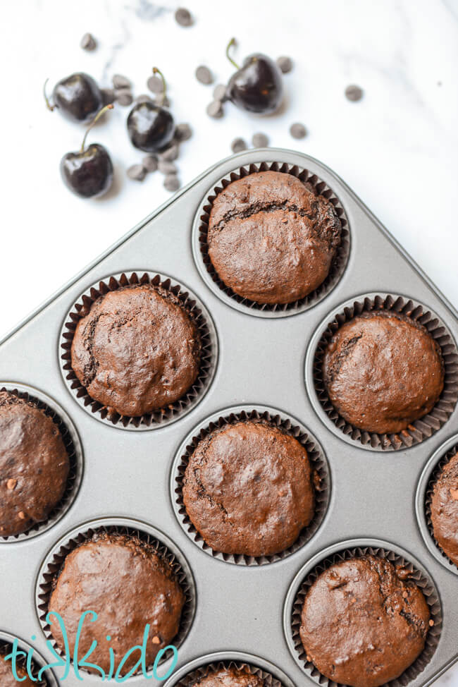 Freshly baked chocolate cherry muffins in a muffin tin.