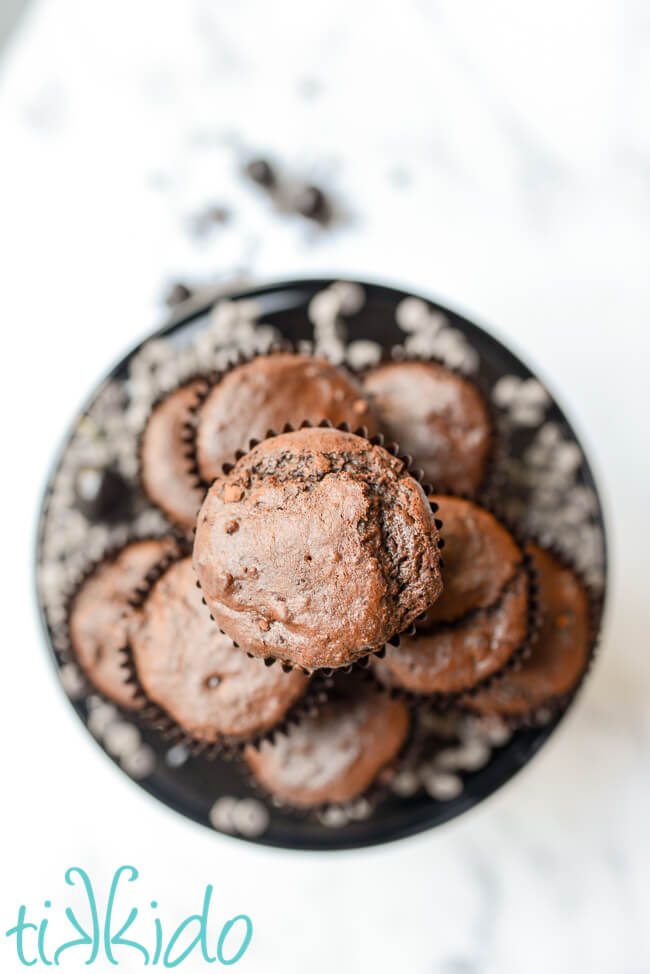 Stack of cherry chocolate muffins on a black cake plate.