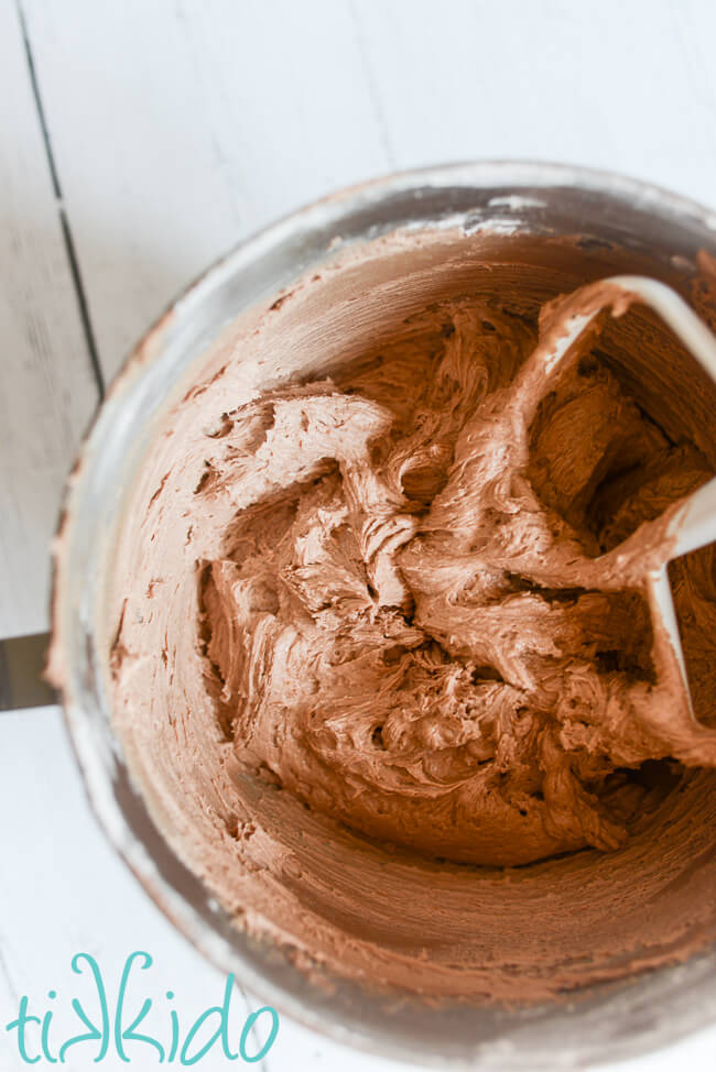 Kitchenaid mixer bowl filled with chocolate American buttercream icing.