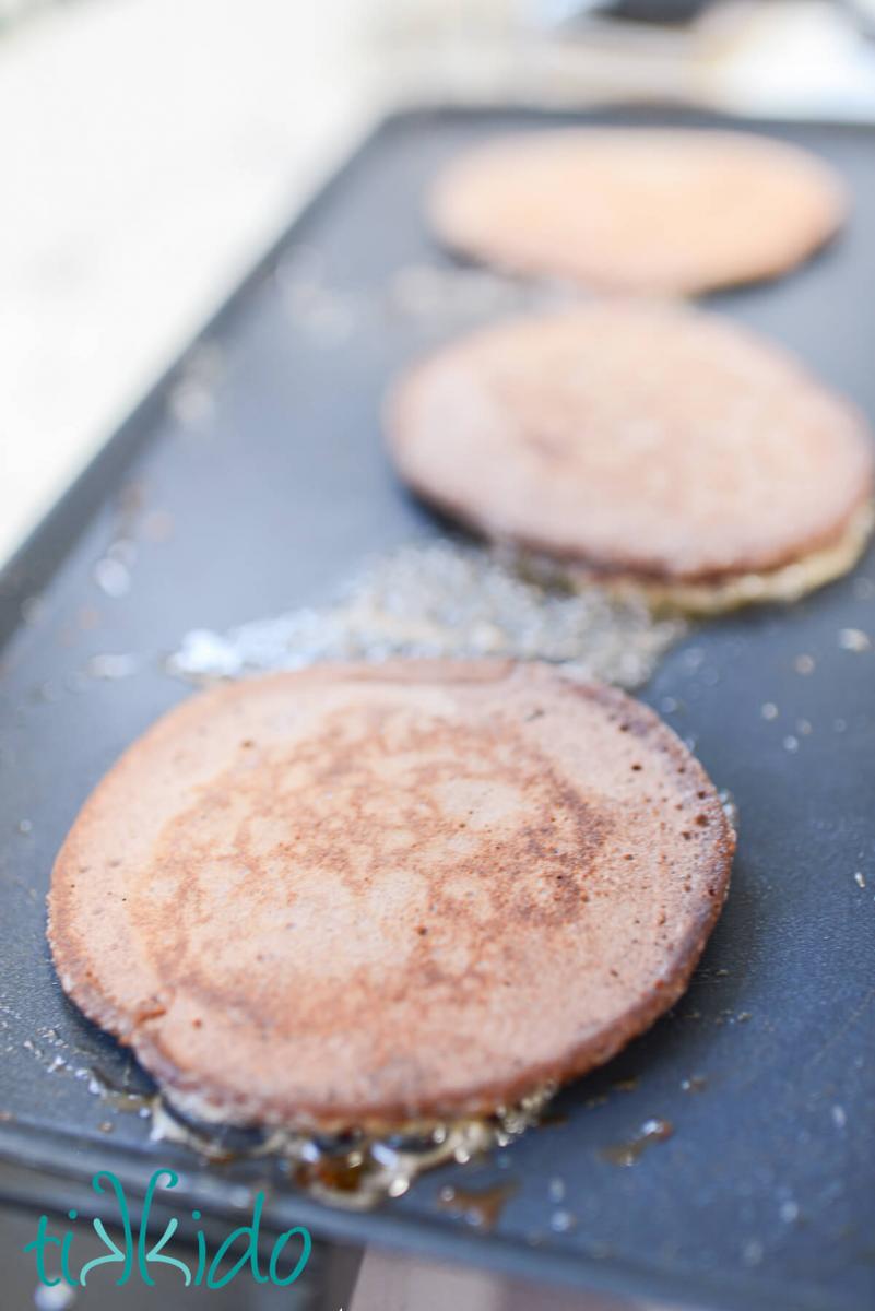 Chocolate Pancakes cooking on an electric griddle.