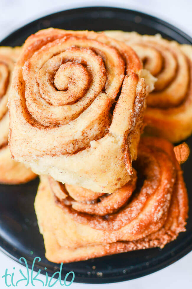 Cinnamon rolls stacked on a black plate.