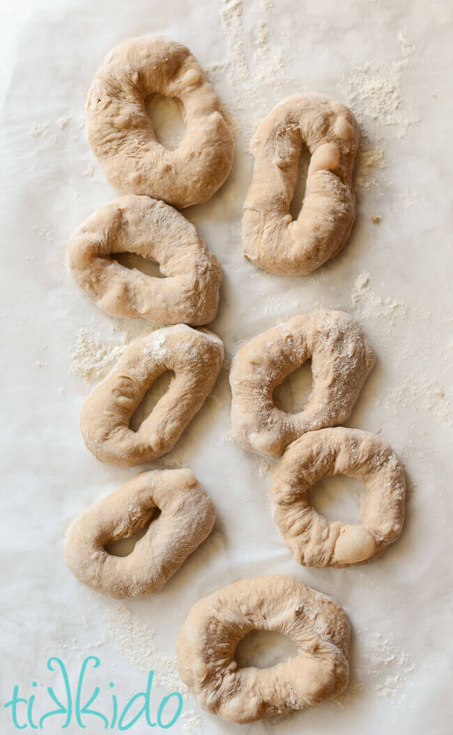 Cinnamon bagels dough shaped into bagel shapes on a white marble surface.