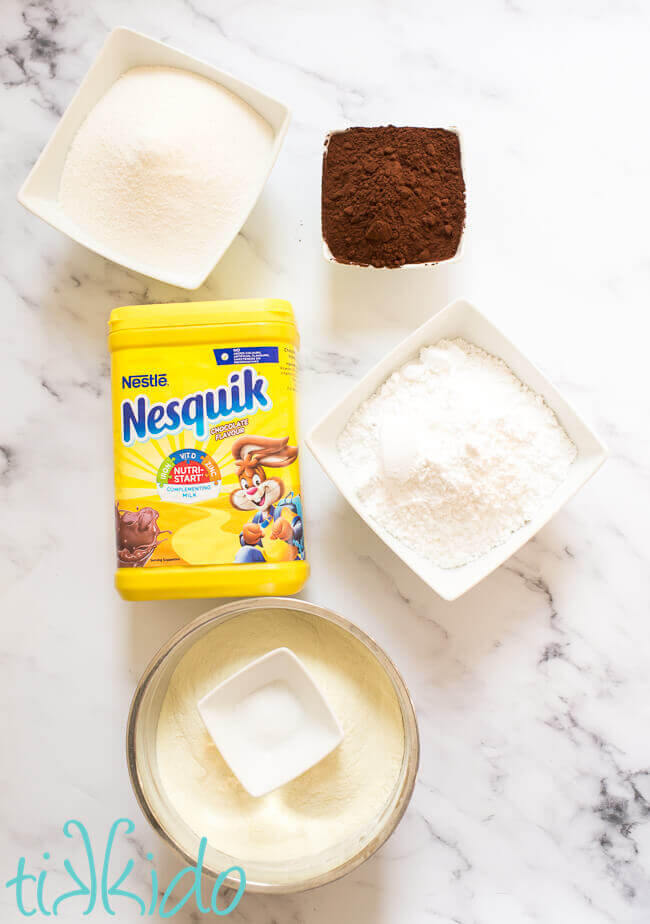 Homemade hot chocolate mix ingredients on a white marble background.