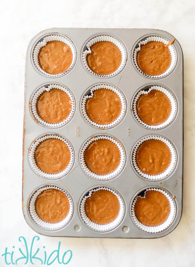 Unbaked coffee cupcakes in a cupcake tin on a white marble surface.