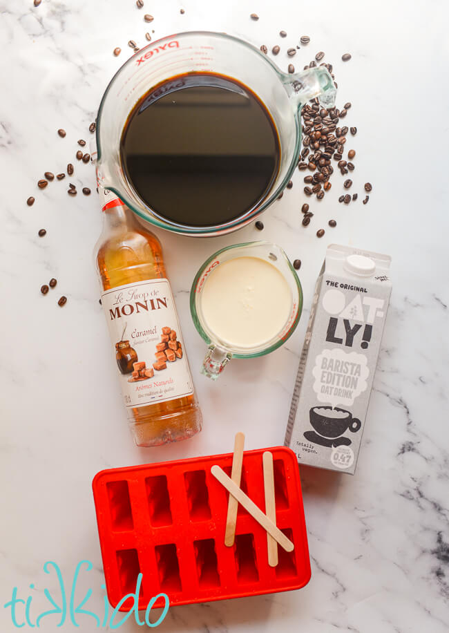 Ingredients for coffee popsicles on a white marble surface.