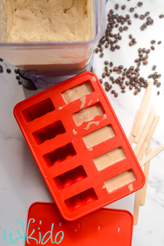 Coffee Popsicle mixture being poured in a red silicone popsicle mold.
