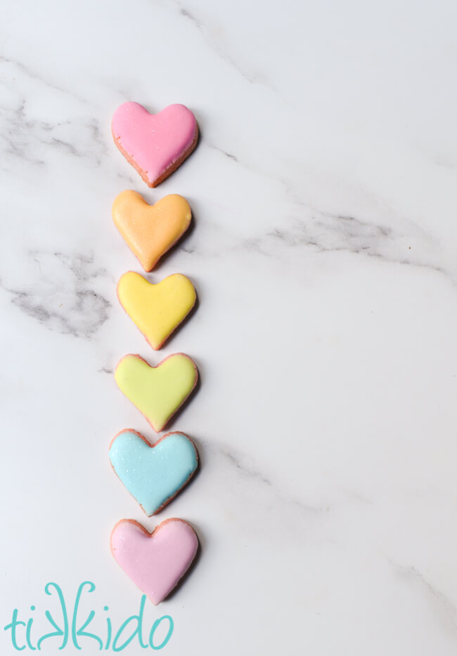 Conversation Heart Cookies arranged in a vertical line on a white marble surface.