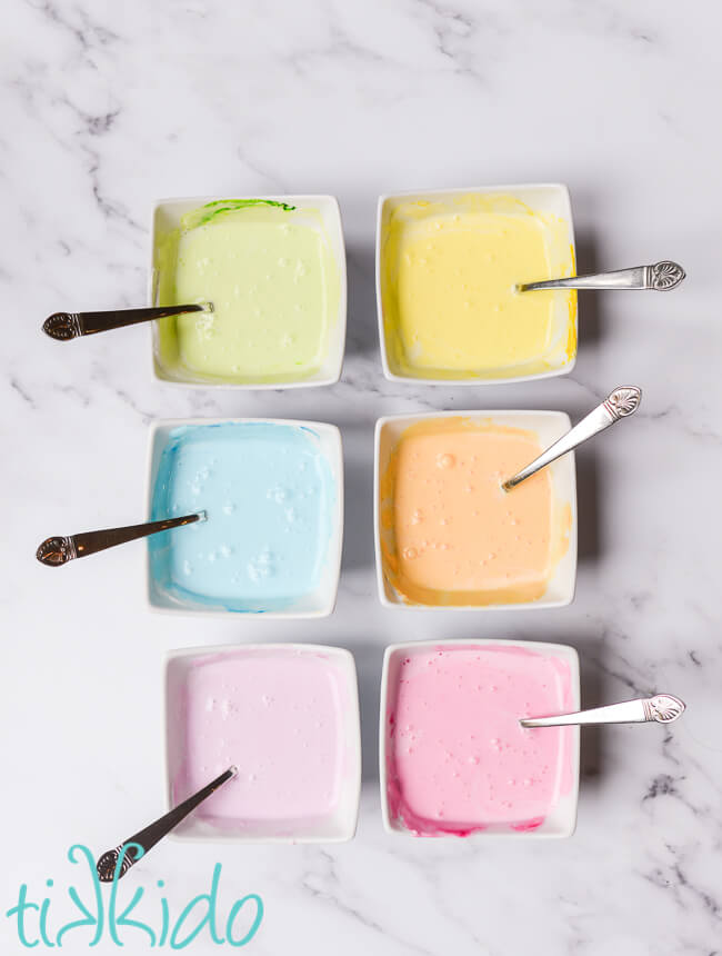 Royal icing in white bowls, colored like conversation hearts candies, for making Conversation Heart Sugar Cookies