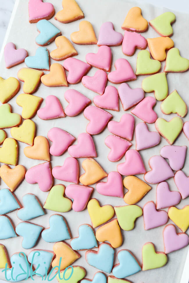 Tiny heart shaped sugar cookies covered in pastel colors to make conversation heart sugar cookies.