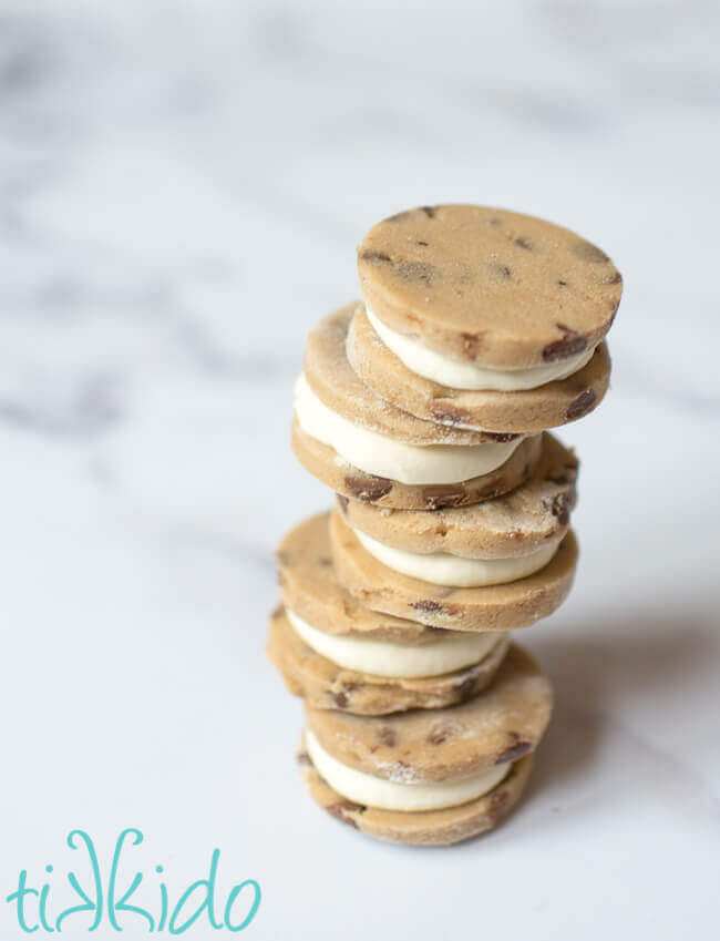 Cookie dough ice cream sandwiches stacked on a white marble surface.