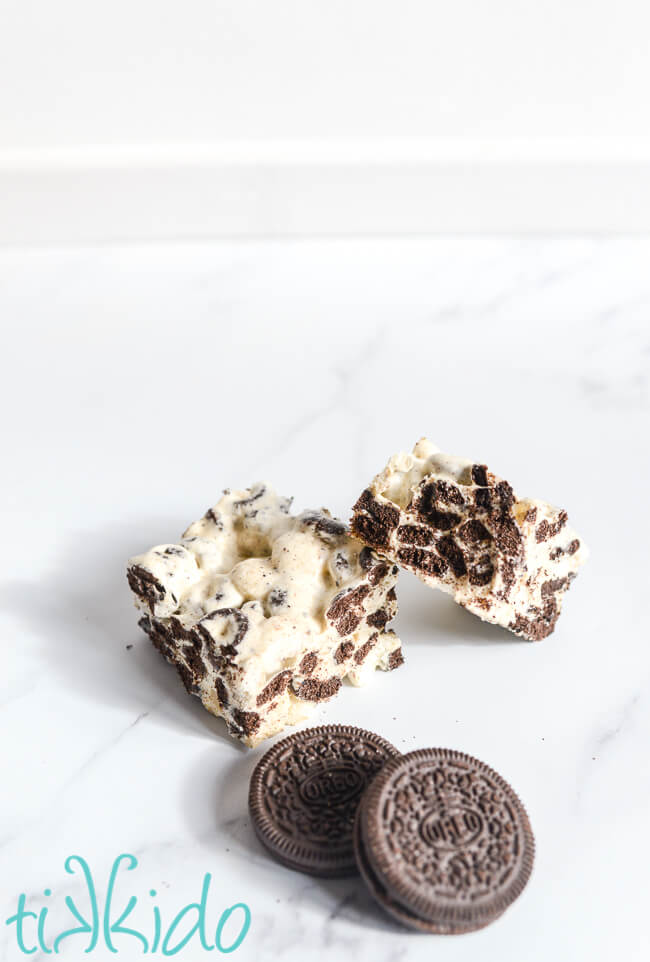 Two Cookies and cream cereal treats on a white marble surface next to two reo cookies.