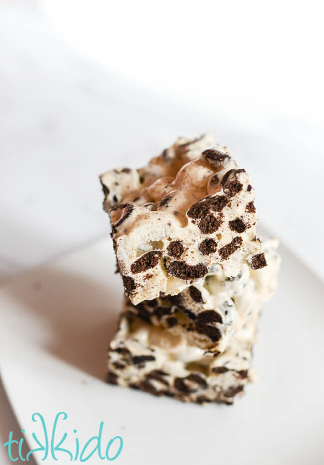 Three Cookies and Cream Cereal Treats stacked on a white plate.