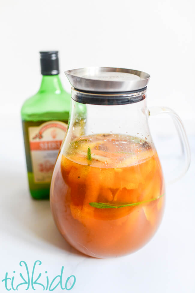 Homemade cornish shrub being made in a lidded glass pitcher, with a bottle of commercial Cornish shrub cordial in the background.