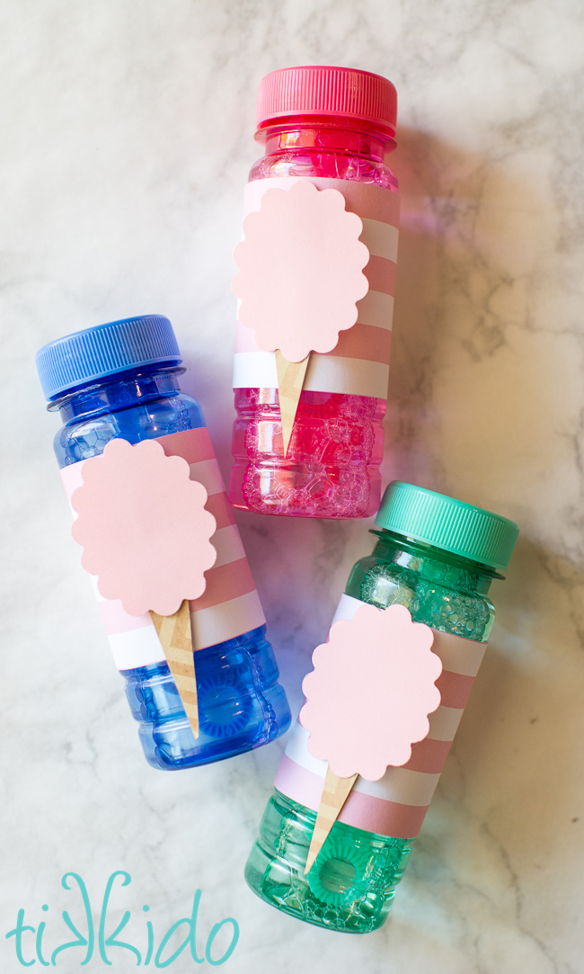 Three cotton candy party bubble favors on a white marble background.